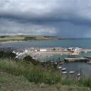 Zicht op Stonehaven vanaf een heuvel. Donkere wolken pakken zich samen boven zee